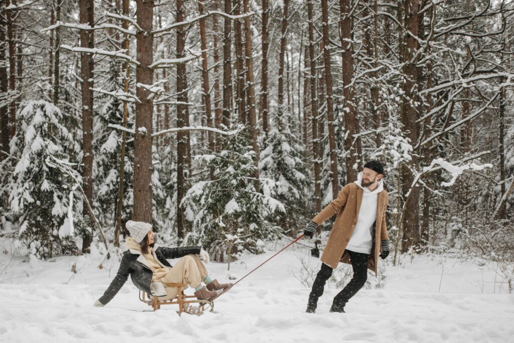 Romantic winter scene of couple enjoying a sleigh ride in a snow-covered forest.